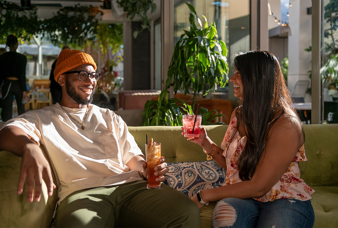 Friends sitting together on couch with cocktails.