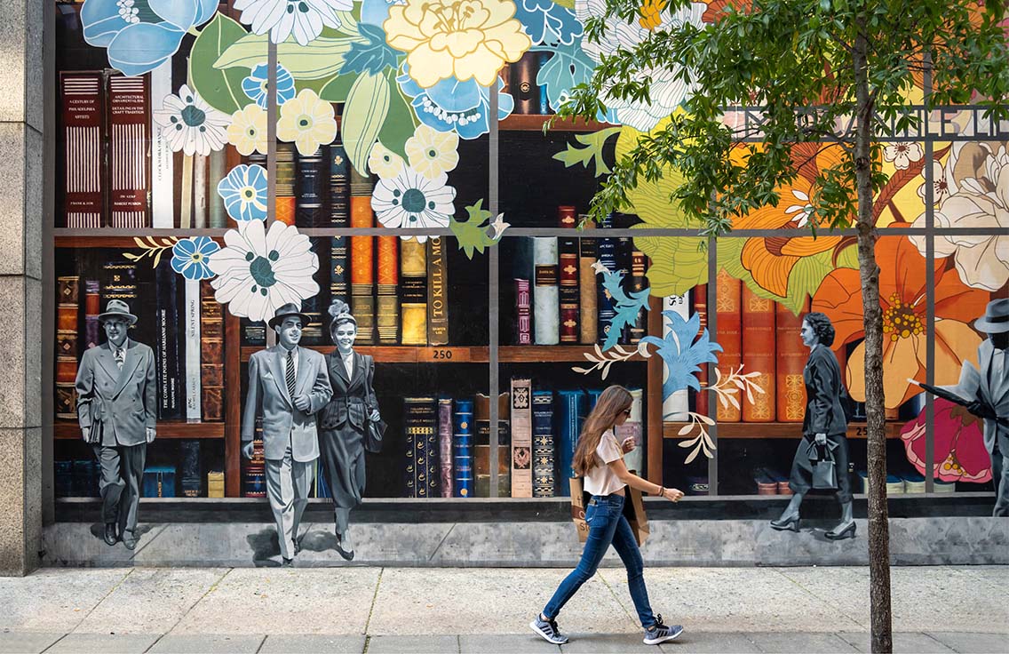 Person walking in front of large painted wall mural.